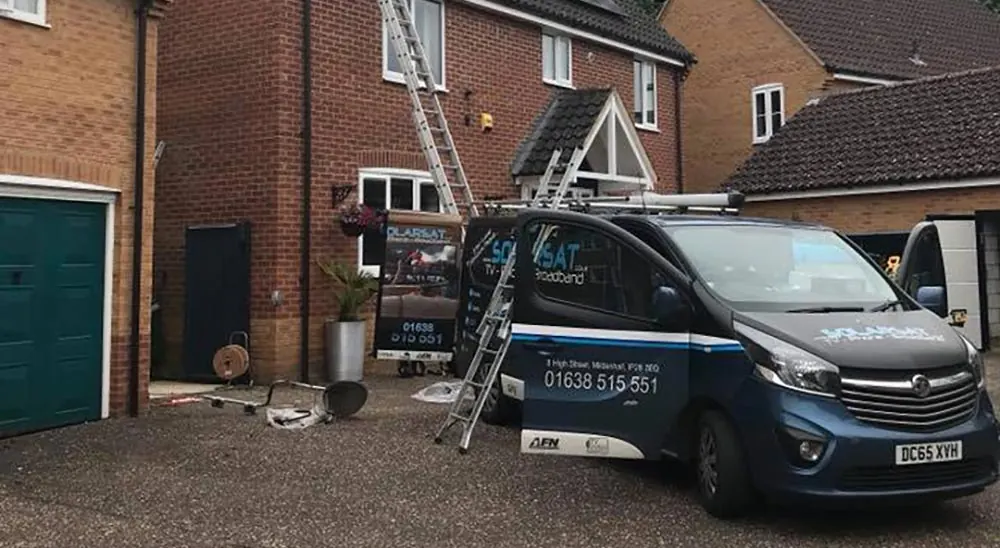 Solarsat branded van parked outside a house during an installation, with a ladder against the roof