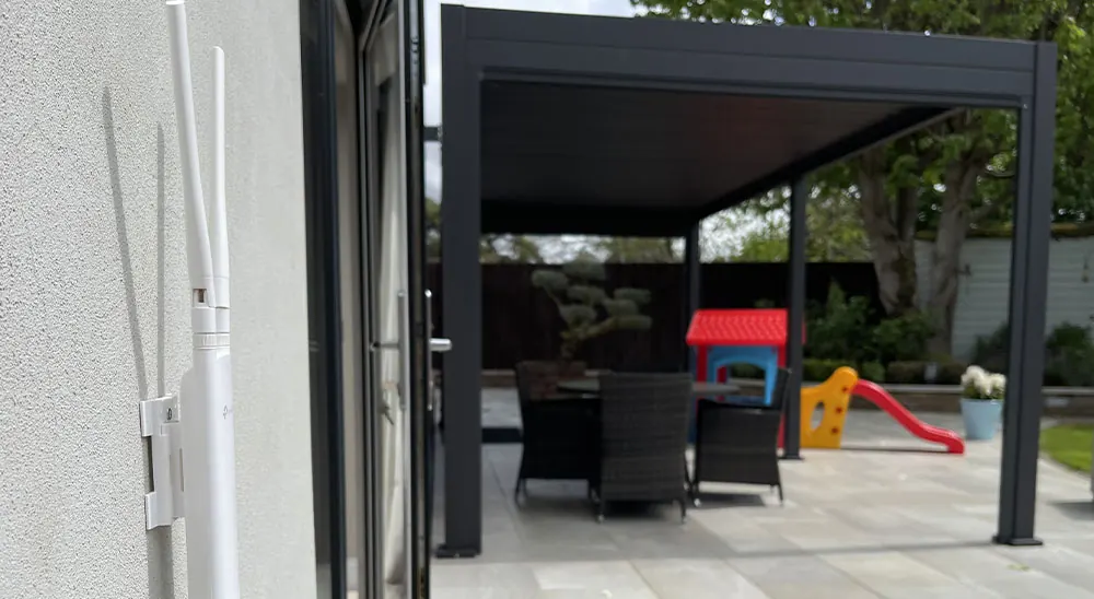 Weatherproof Wi-Fi antenna fitted to an outside wall, with a covered garden patio nearby