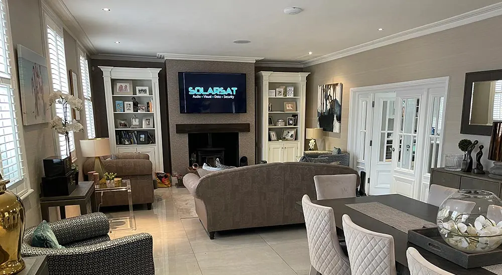 Open-plan living room with a wall-mounted TV showing the Solarsat logo above a fireplace