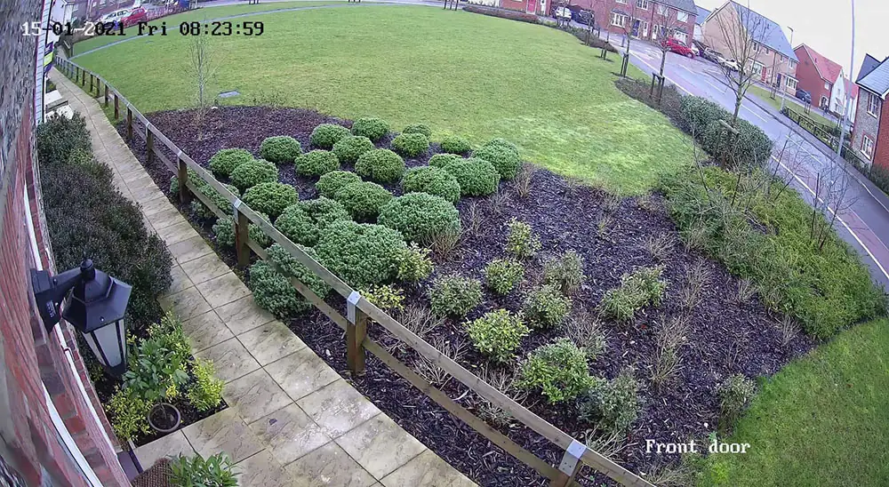 Full-colour CCTV camera footage of a front garden and driveway in daylight