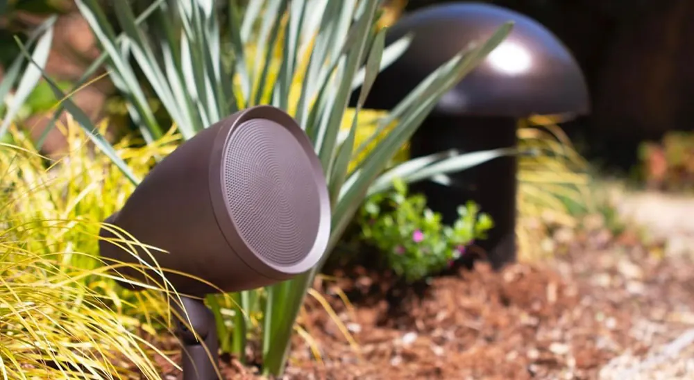 Outdoor garden speakers installed among plants and shrubs in a garden border